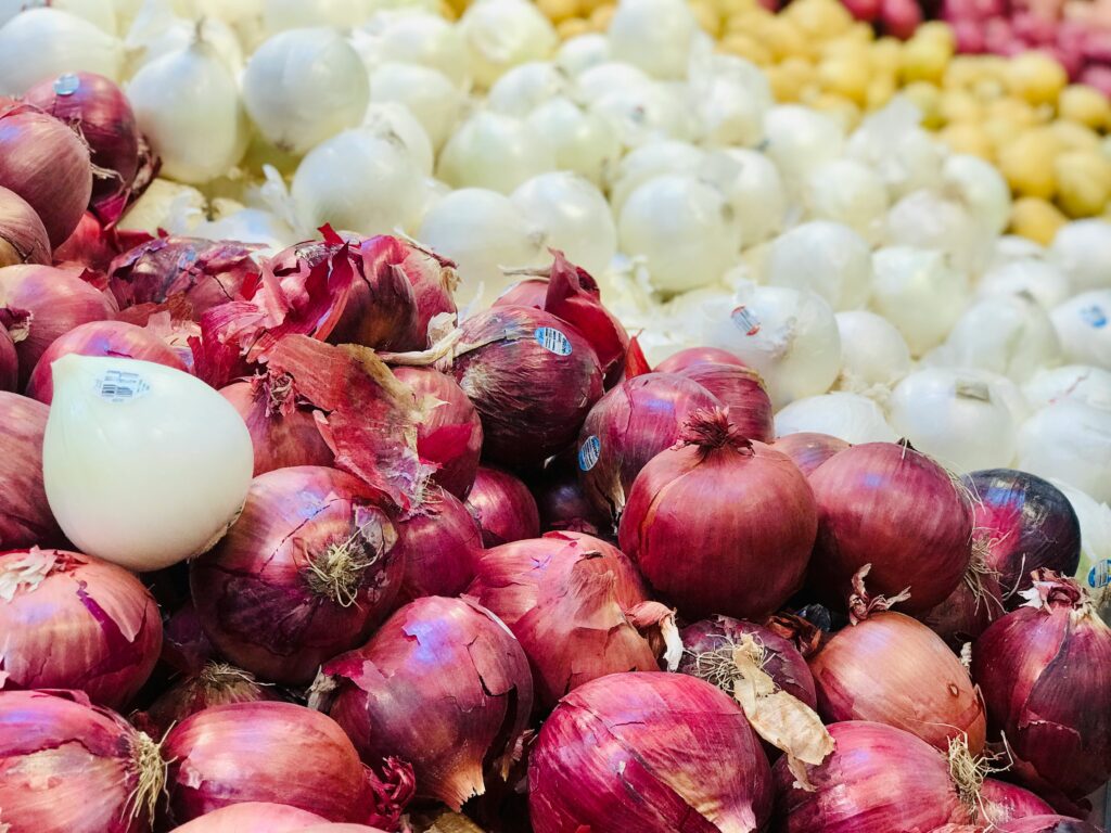 An organized pile of white and red onions that are a part of our fresh produce offerings.